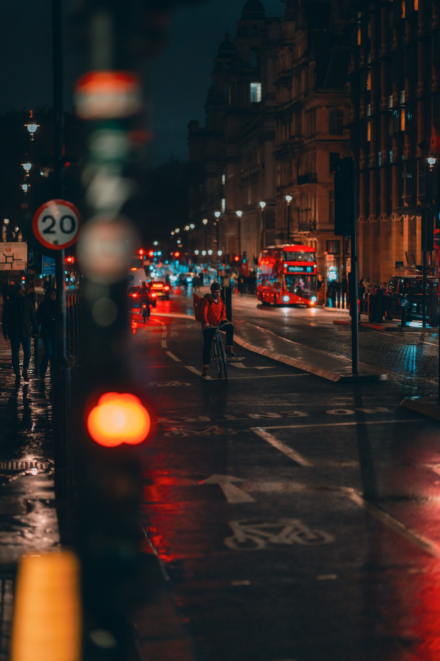 Rainy London street at night with a red bus and wet road reflections